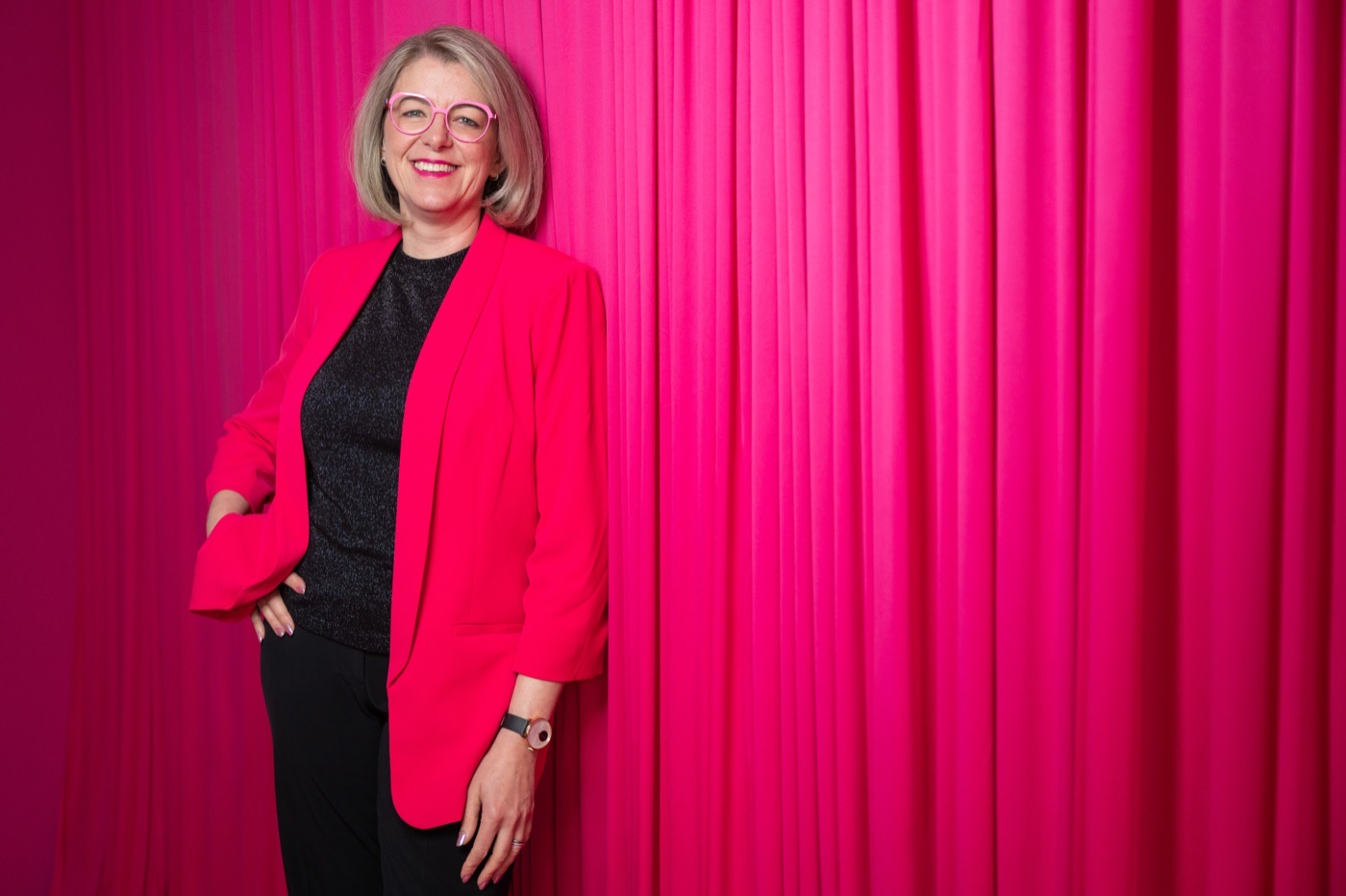 Rebecca Maria Jesske im pinken Blazer vor einem pinken Vorhang
